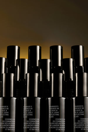 Rows of black Allies of Skin Founder's Essence 56 Ellagic & P.A.D. Light Reflecting Fluid bottles, business lifestyle banner